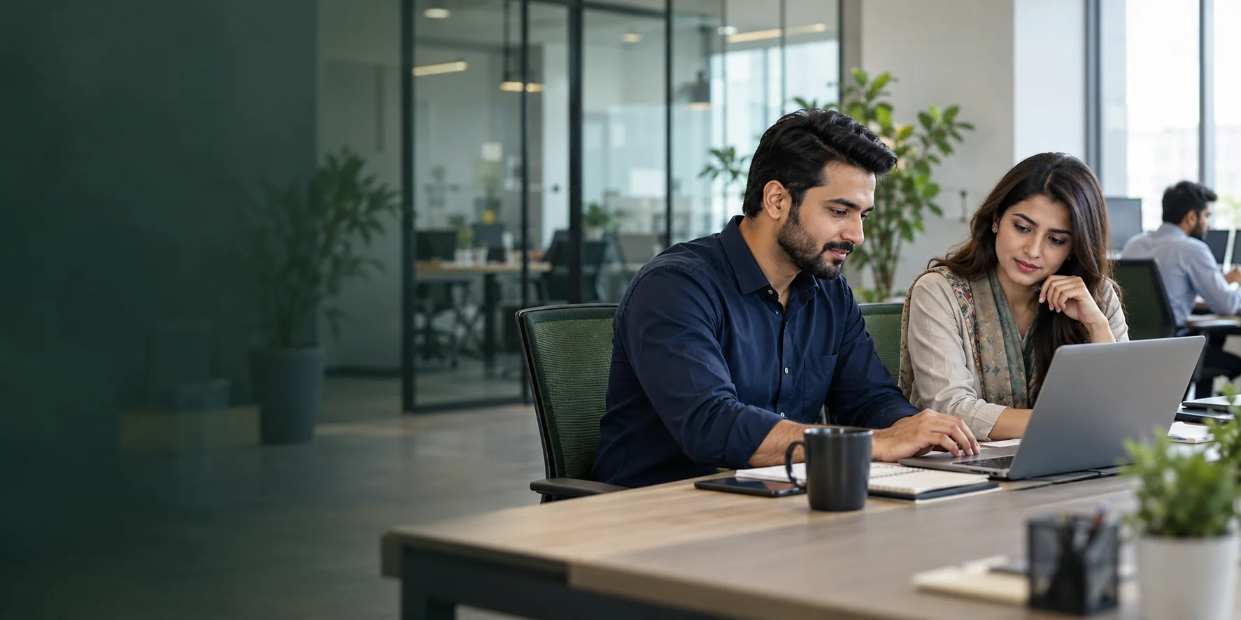 Professionals collaborating at a laptop in a modern office